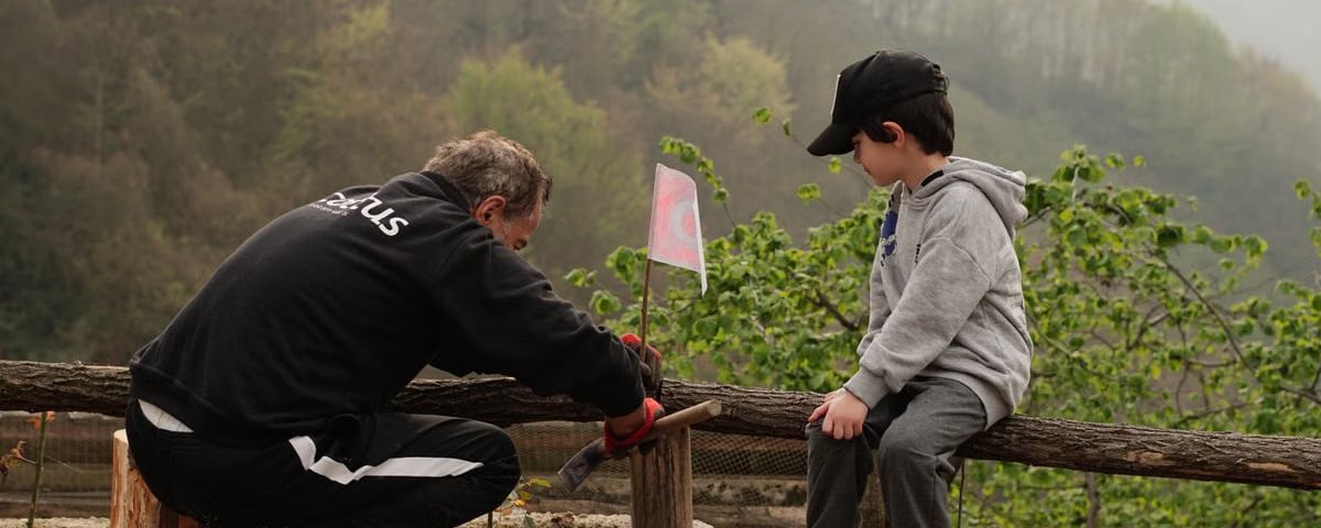 An older man and a boy engage in outdoor activities in a foggy rural setting, surrounded by nature.